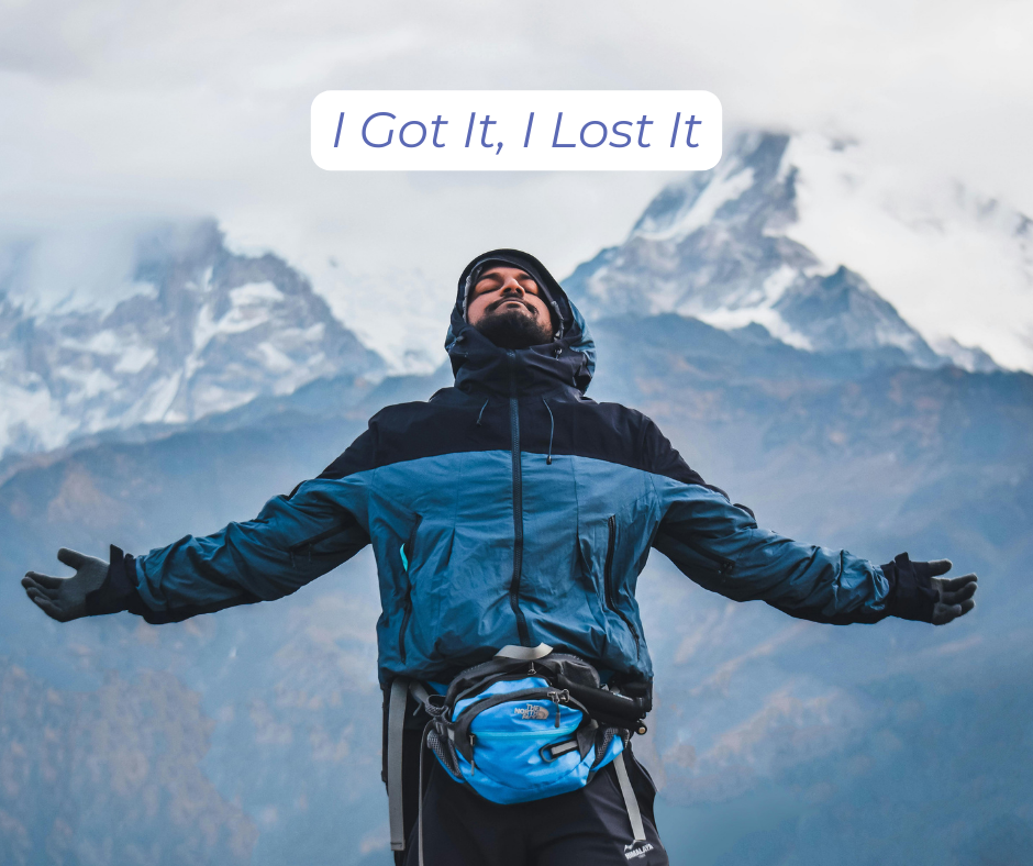Man on top of a snowy mountain looking up with arms stretched out