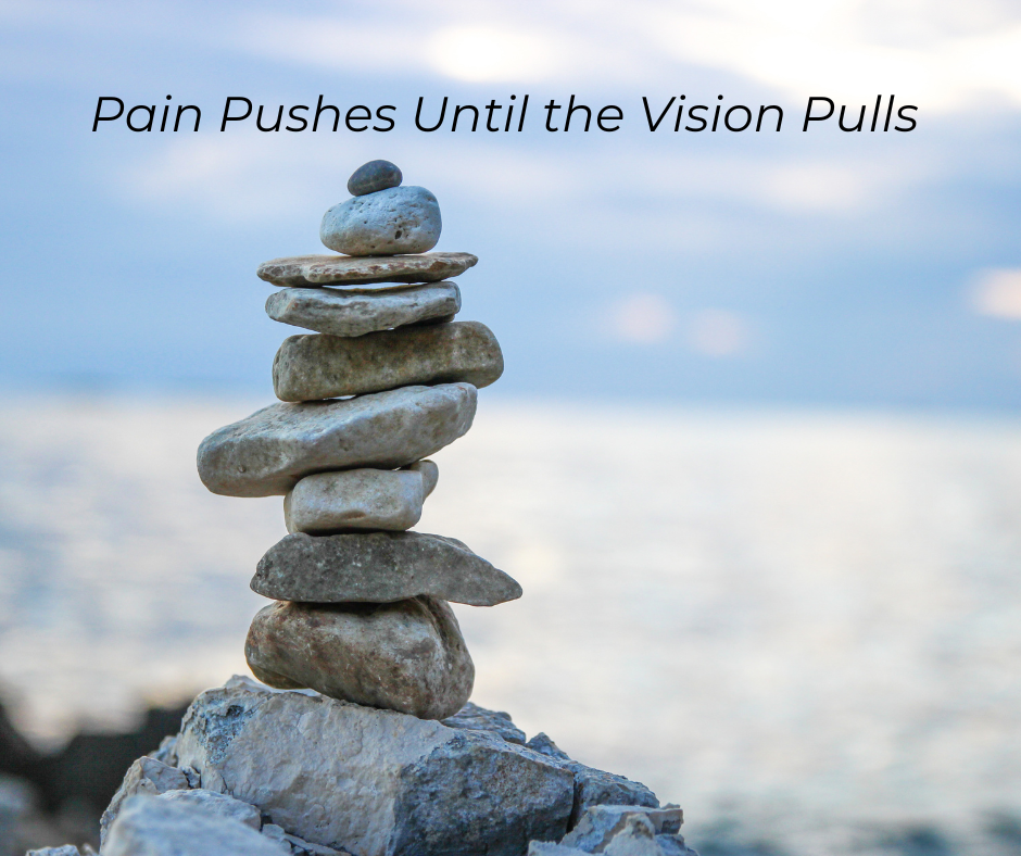 Stones stacked and balanced near the ocean. Text: Pain Pushes Until the Vision Pulls
