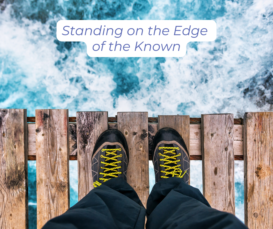 Legs and shoes of a person standing at the edge of a wooden bridge looking down into the churning water below.
