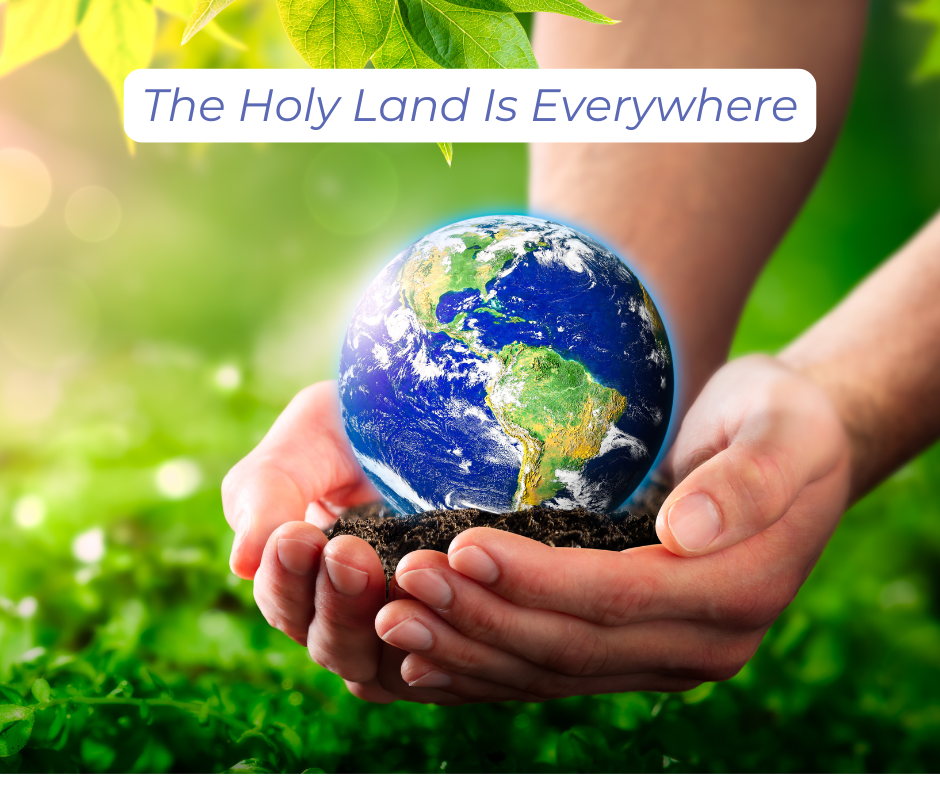 Hands holding a globe of earth with lush green landscape in the background.