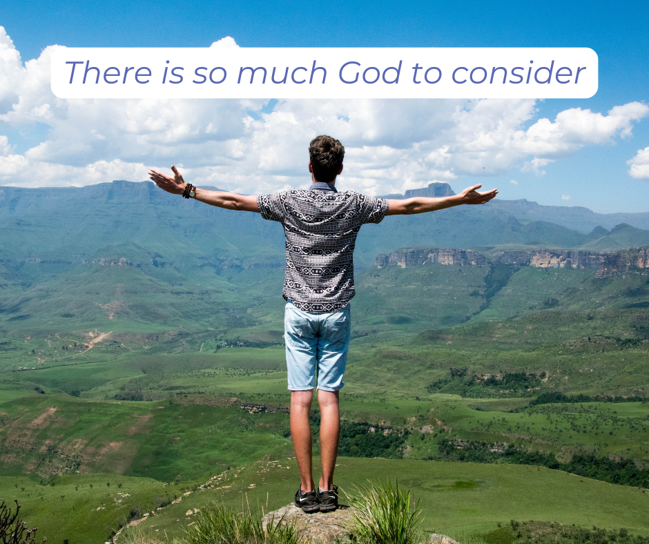 A man on top of a mountain with arms stretched out facing the vast surroundings.